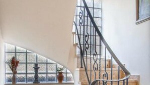 A staircase with ornate metal railings and a view of the outside through a window. - Familiehuis Dolve (Muerlenbach)