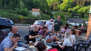 A group of people dining outdoors at a table with plates, cutlery, and drinks. - Familiehuis Dolve (Muerlenbach)