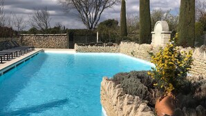 A clear blue swimming pool with stone walls and a stone pathway leading to the pool. - Le Bastidon de l'Olivier (Gordes)