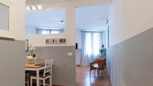 Un pasillo estrecho que conduce a un comedor con una mesa y sillas, un letrero que dice "CUISINE" y una planta.