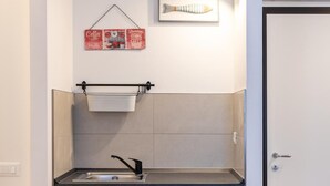 Una cocina compacta con un lavamanos, armarios de madera, una lámpara colgante y un cuadro en la pared.