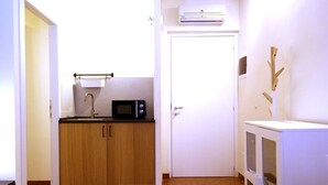 Cocina compacta con armarios de madera, un microondas y un lavabo.