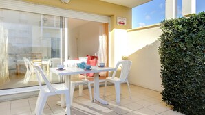 Un balcon avec une table et des chaises, une fenêtre avec des rideaux et un panneau sur le mur.