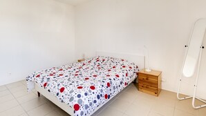 Une chambre à coucher comprenant un lit, une table de chevet, un miroir et un luminaire suspendu.