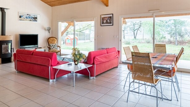 Un amplio salón con un sofá rojo, una mesa de centro, sillones de mimbre y una chimenea.