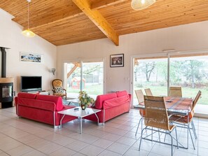 A spacious living area with a red sofa, a coffee table, wicker chairs, and a fireplace.
