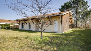Una casa de dos pisos con techo de tejas, un porche cubierto y un árbol pequeño en el jardín delantero.
