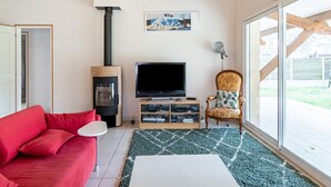 Una sala de estar con un sofá rojo, un televisor, una chimenea y un ventanal grande.