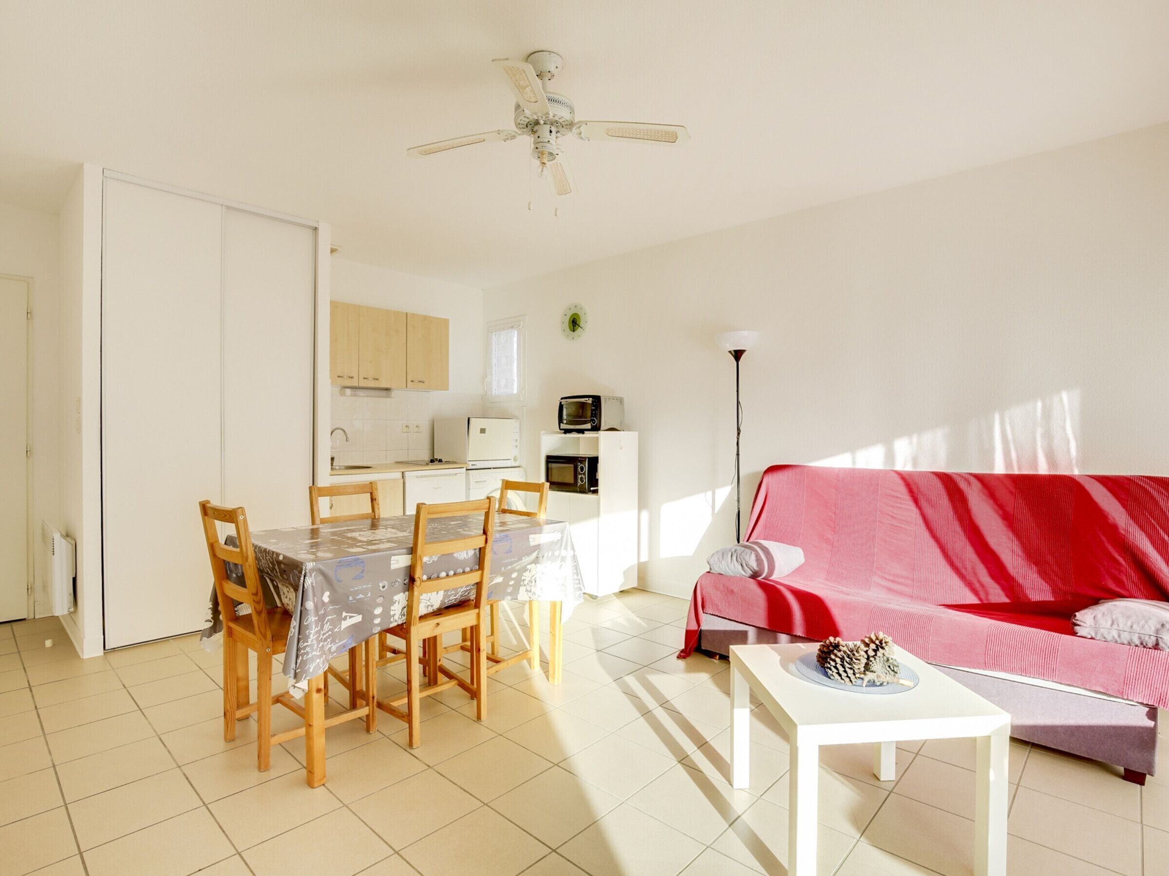 A compact living space with a dining area, kitchenette, and a red sofa.