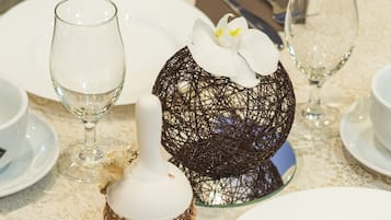 Un tavolo apparecchiato con piatti bianchi, posateria e un vaso di vetro decorato con un'orchidea.