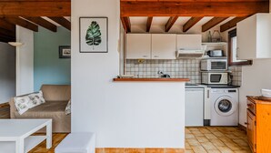 A compact kitchen with a washing machine, a microwave, and a small countertop. - Charming 4-Person Home, Quiet Area Near Beaches, Biscarrosse (Biscarrosse Plage)