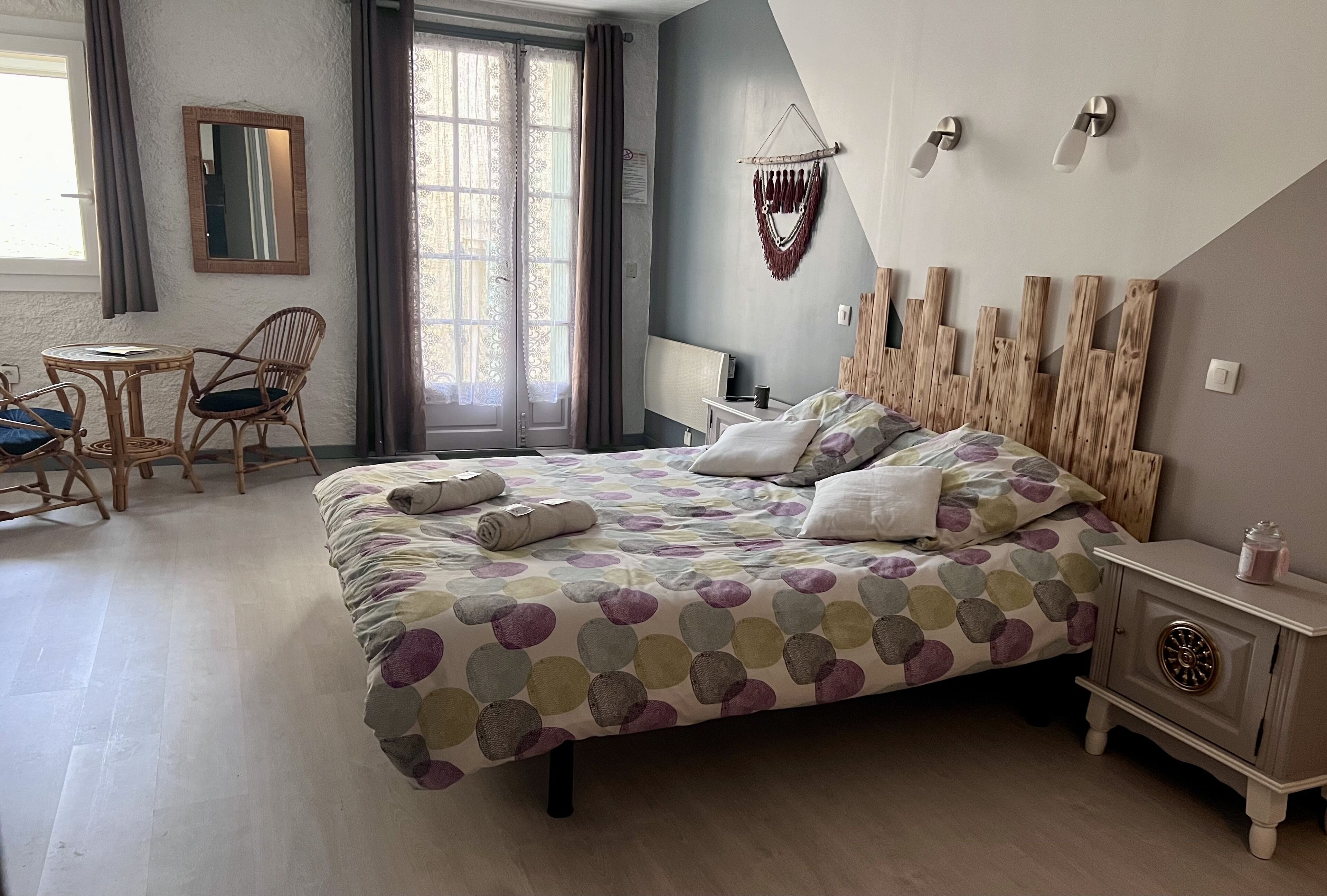 Une chambre à coucher comprenant un lit, une table de chevet, une chaise, un bureau et une fenêtre avec des rideaux.