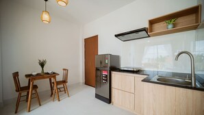 A modern kitchen with a refrigerator, wooden cabinets, a sink, and pendant lights. - BB's Cozy House & Apartment (Da Nang)