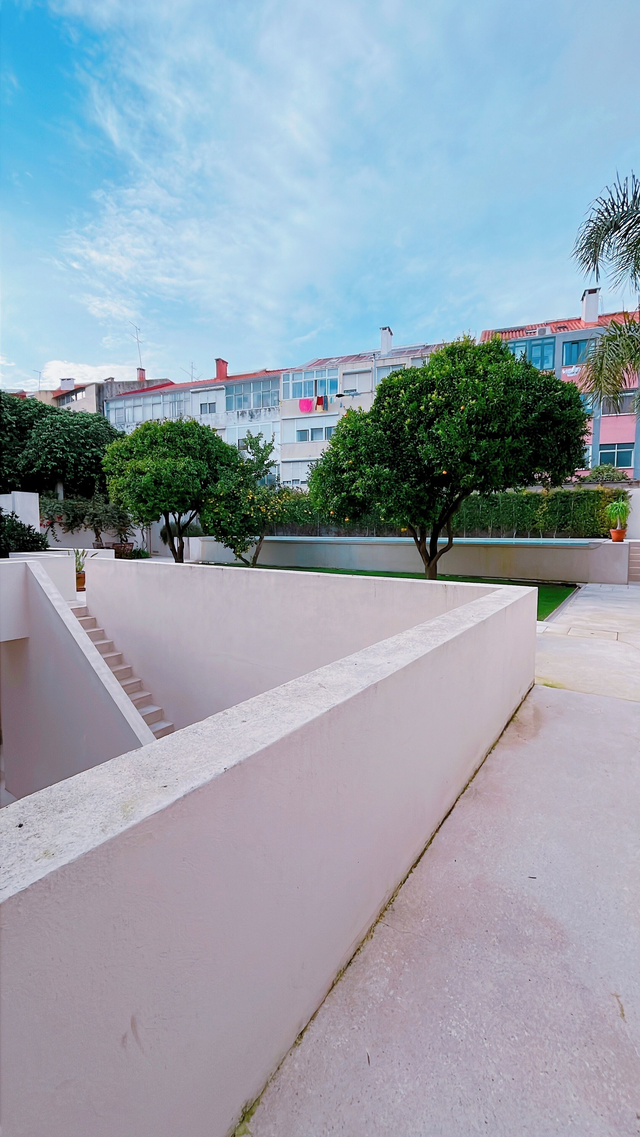 Un'area esterna moderna con struttura in cemento, una scala e vista su edifici residenziali sullo sfondo.