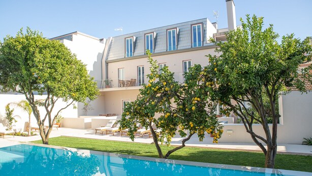Una casa moderna con piscina, mobiliario de exterior y un jardín cuidado.