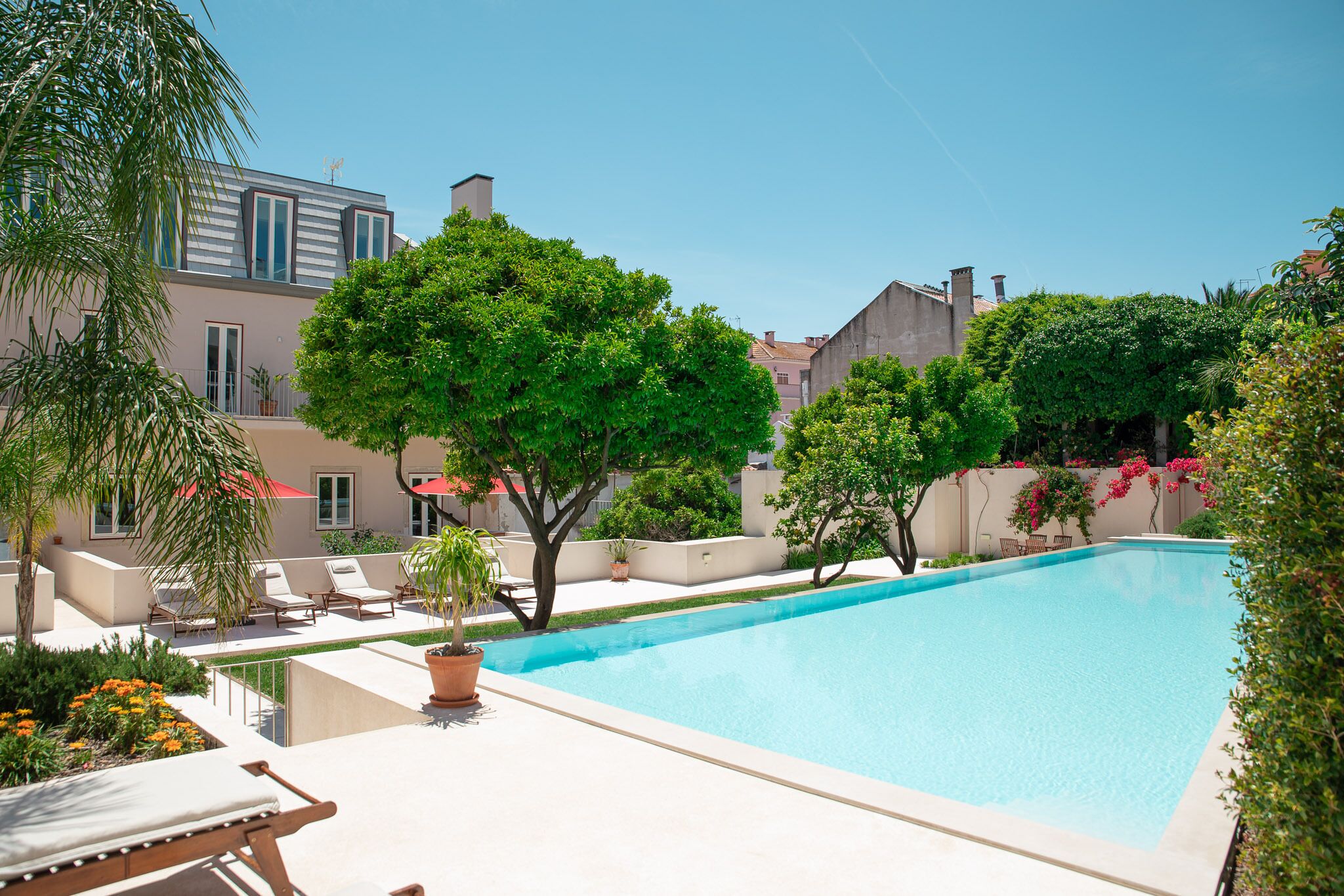 A swimming pool with lounge chairs and potted plants.