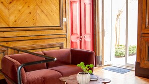 Un interior de madera con una puerta roja, un sofá rojo y una pequeña mesa con una planta.