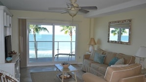 A living room with a view of the ocean, a ceiling fan, a sofa, a coffee table, and a television. - Beachcomber unit 404 (Longboat Key)