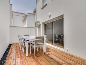 A patio with a table and chairs, a sliding glass door, and a white exterior wall. - Duplex 6 ppl near ocean, center, WIFI, pets OK (Biscarrosse Plage)