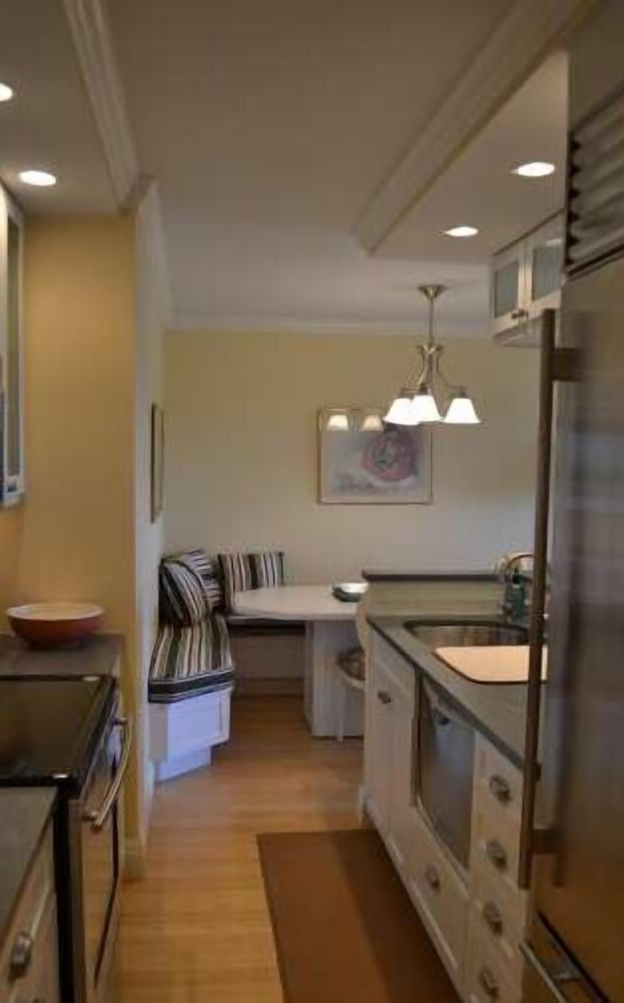 A compact kitchen with a central island, a dining area with a striped chair, and a refrigerator.