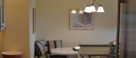 A compact kitchen with a central island, a dining area with a striped chair, and a refrigerator.