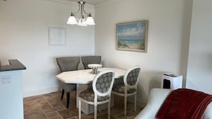 A dining area with a table and chairs, a painting on the wall, and a ceiling light fixture. - Beachcomber unit 603 (Longboat Key)
