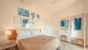 Een slaapkamer met een bed, nachtkastjes, een kledingkast en kunst aan de muur.