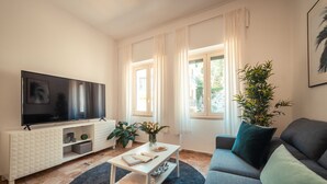 Een moderne woonkamer met een flatscreen televisie, een bank, een salontafel en een potplant.