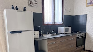 Une cuisine compacte équipée d’un réfrigérateur, d’un four à micro-ondes, d’une machine à café, d’un évier et d’un four.