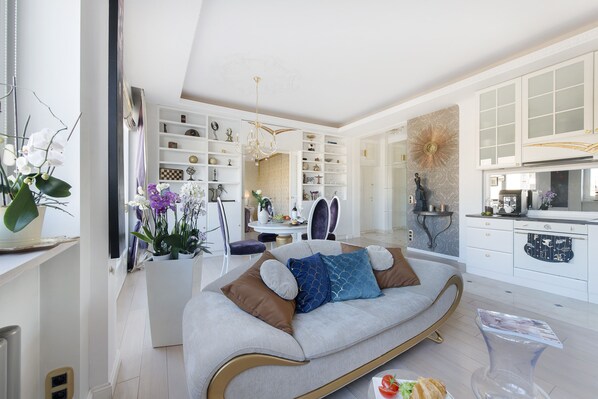 A modern living room with a sofa, dining area, and kitchen.