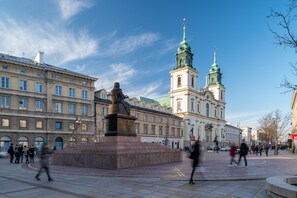 A public square with a statue, historic buildings, and a church with a green spire.