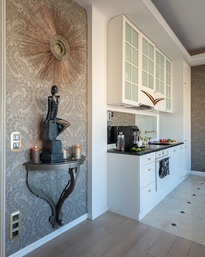A modern kitchen with white cabinetry, a built-in oven, and a decorative wall piece.