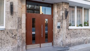 A stone building with a wooden double door, a small window with plants, and a plaque on the wall. - P&O Apartments Tamka 4 (Warsaw)