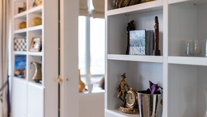 A white shelving unit with various items including a book titled 'WONDERS', a clock, and decorative objects. - P&O Apartments Tamka 4 (Warsaw)
