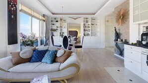 A spacious living area with a sofa, a dining table, and a kitchen area with cabinets and a decorative wall piece. - P&O Apartments Tamka 4 (Warsaw)