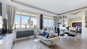 En moderne stue med sofa, sofabord i klart glas og et spiseområde med bord og stole.