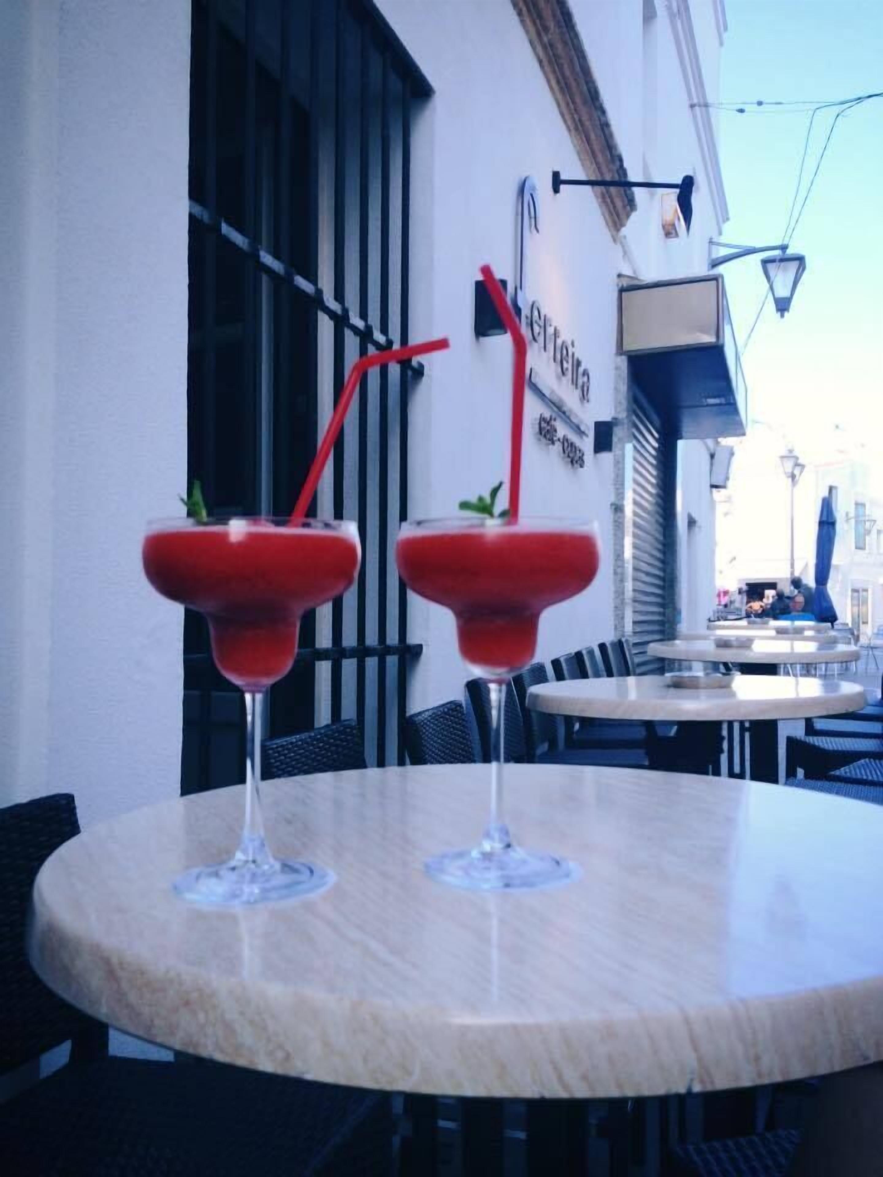 Two martini glasses with red straws on a round table.