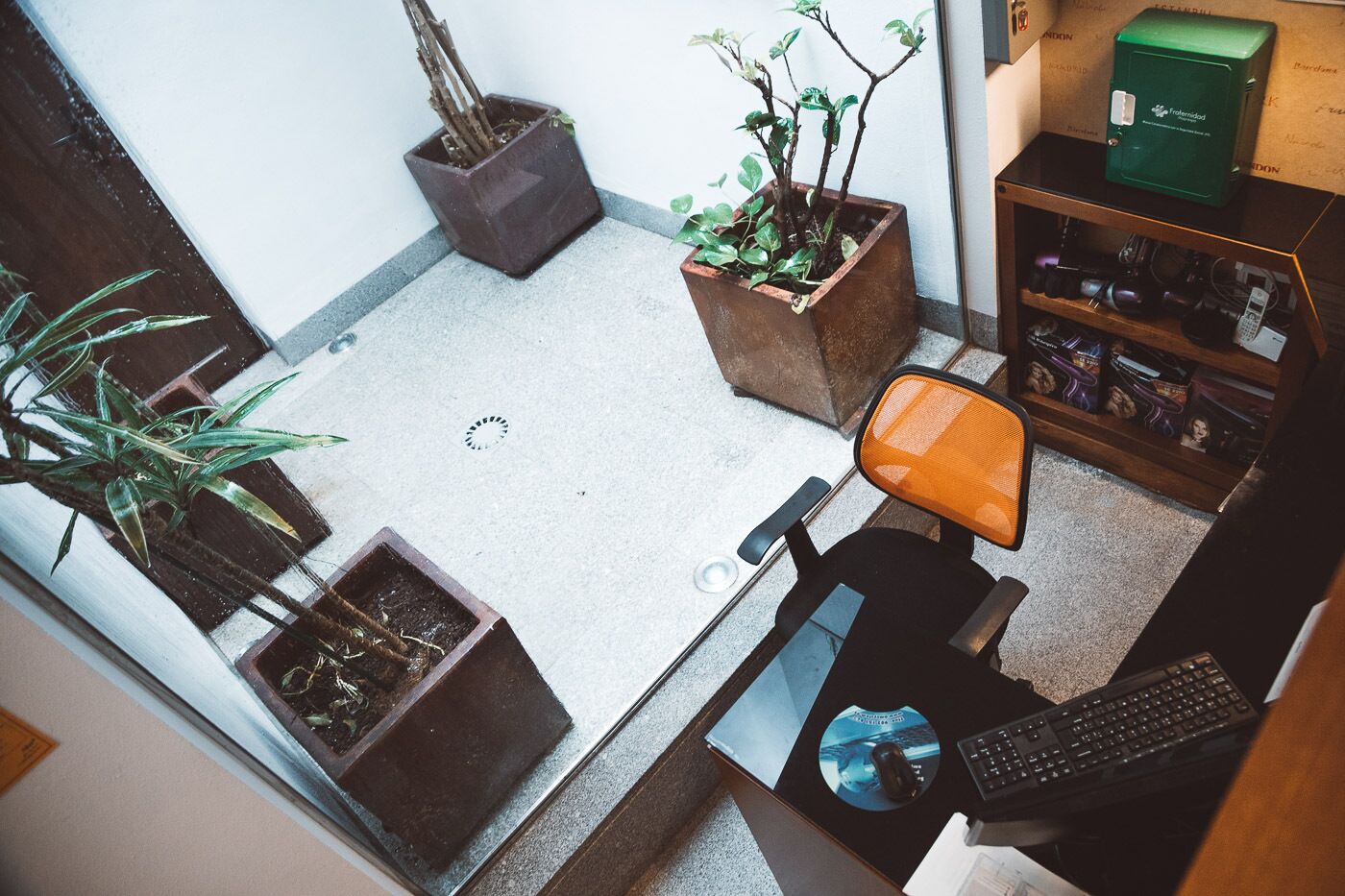 A small office space with a desk, chair, keyboard, mouse, and two potted plants.