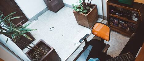 A small office space with a desk, chair, keyboard, mouse, and two potted plants.