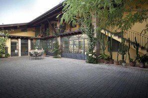 Ein Innenhof mit Backsteinfassade, einem Esstisch mit Stühlen, Topfpflanzen und einer Treppe.