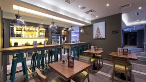 A bar area with stools, tables, and a bar counter with bottles. - Premier Inn Liverpool Lime Street (Liverpool)