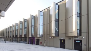 A modern hotel facade with a series of vertical windows and doors, a visible entrance, and a clear sky. - Premier Inn Liverpool Lime Street (Liverpool)
