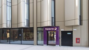 A hotel entrance with a prominent sign for Premier Inn, large windows, and a fire alarm box. - Premier Inn Liverpool Lime Street (Liverpool)