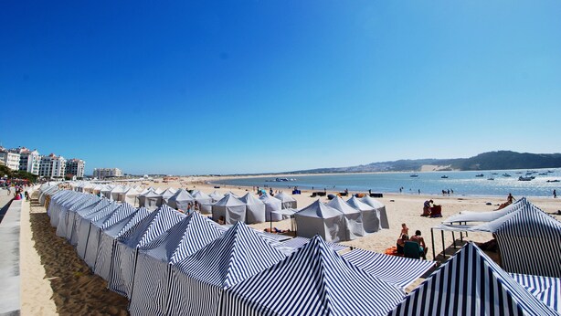 Ein Strand mit gestreiften Strandzelten und einem sandigen Ufer.