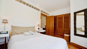 Ein Schlafzimmer mit einem Bett, Nachttisch, Lampe und einem Holzschrank.
