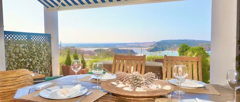 An outdoor dining area with a view of the landscape, wooden furniture, and a table set for two.