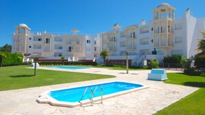 A modern hotel with a swimming pool, multiple balconies, and a well-maintained lawn. - Turtle - 3 bedroom apartment in Nazaré with 2 shared pools and private terrace (Nazaré)