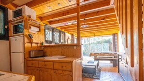 Una cocina funcional con armarios de madera, un refrigerador, un microondas y un lavamanos.