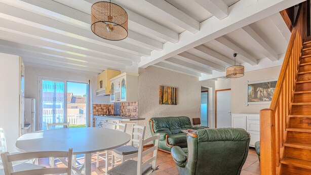 A spacious living area with a green sofa, white chairs, a round dining table, and a kitchen in the background. - Spacious 3-BR House, Sleeps 7, Near Beach & Town, Large Yard, BBQ, Pet-Friendly (Biscarrosse Plage)