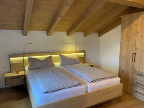 Ein Doppelbett mit hölzernem Kopfteil, zwei Nachttische und ein Kleiderschrank.